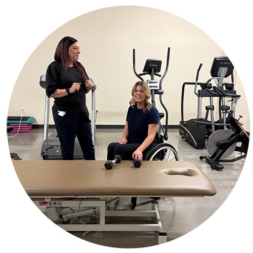 Two people in the gym while one is on a wheelchair